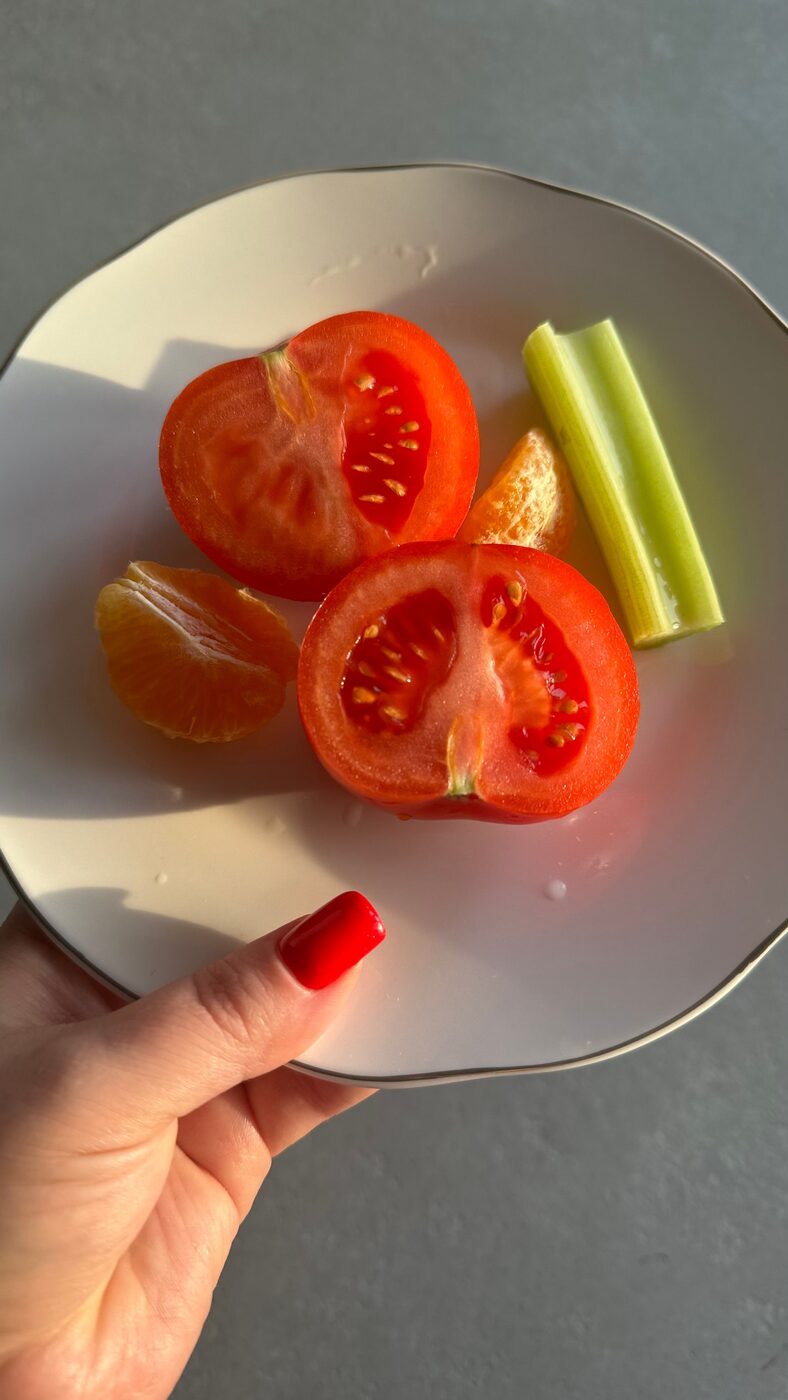 Assiette de tomates fraîches et agrumes tenue à la main